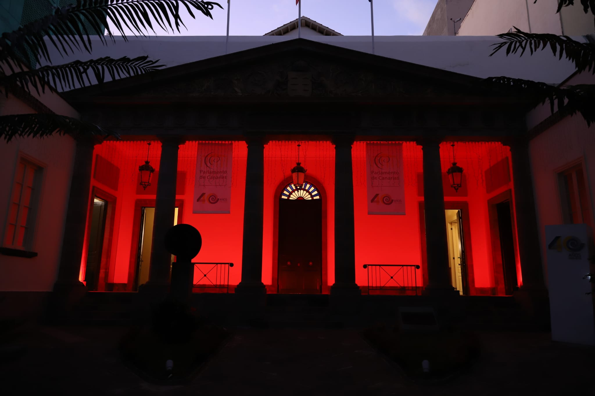 La fachada del Parlamento de Canarias iluminada de color rojo